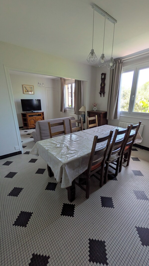Un coin repas comprenant une table, des chaises, un téléviseur et une horloge murale.