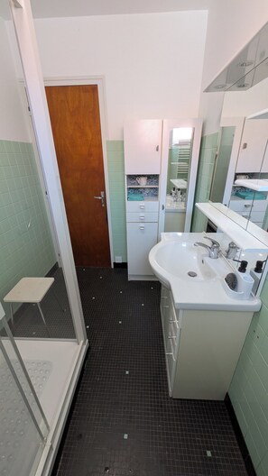 Ein Badezimmer mit Dusche, Waschbecken und Spiegel.