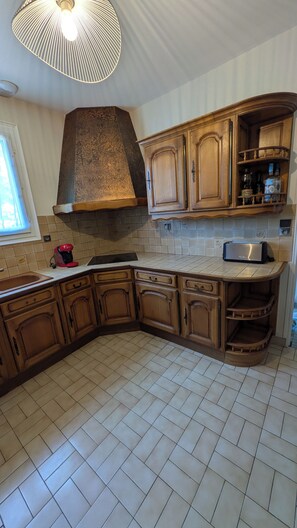 A kitchen with wooden cabinets, a built-in oven, a toaster, and a window with blinds.