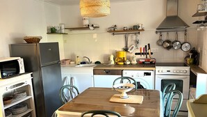 Een praktische keuken met een koelkast, magnetron, vaatwasser, fornuis en diverse keukengerei.