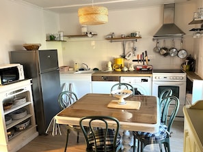 Eine kompakte Küche mit Kühlschrank, Mikrowelle, Geschirrspüler, Herd und verschiedenen Küchenutensilien.