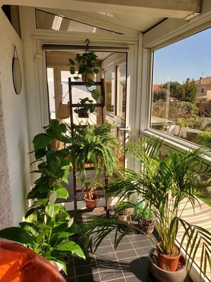 A sunlit balcony with potted plants, a wooden trellis, and a view of the neighborhood. - La Corbusière de Pessac (Pessac)