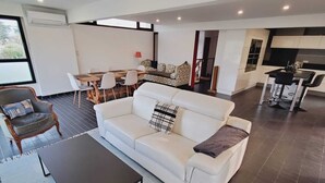 A modern living room with a white sofa, a coffee table, and a dining area with chairs and a table. - La Corbusière de Pessac (Pessac)