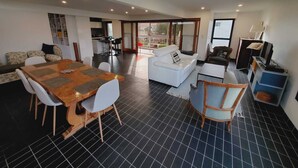 A spacious living area with a dining table, sofas, and a kitchen in the background. - La Corbusière de Pessac (Pessac)