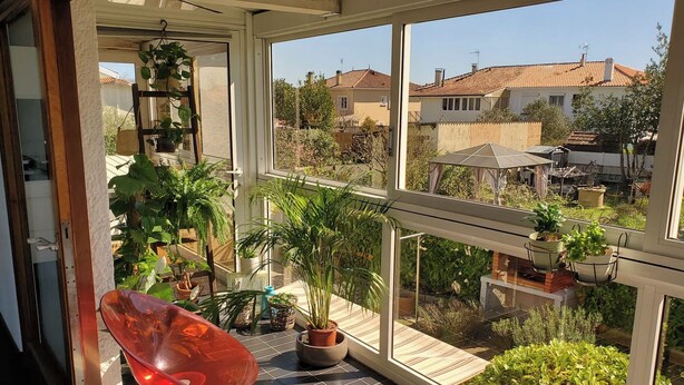 A balcony with potted plants, a red chair, and a view of houses. - La Corbusière de Pessac (Pessac)