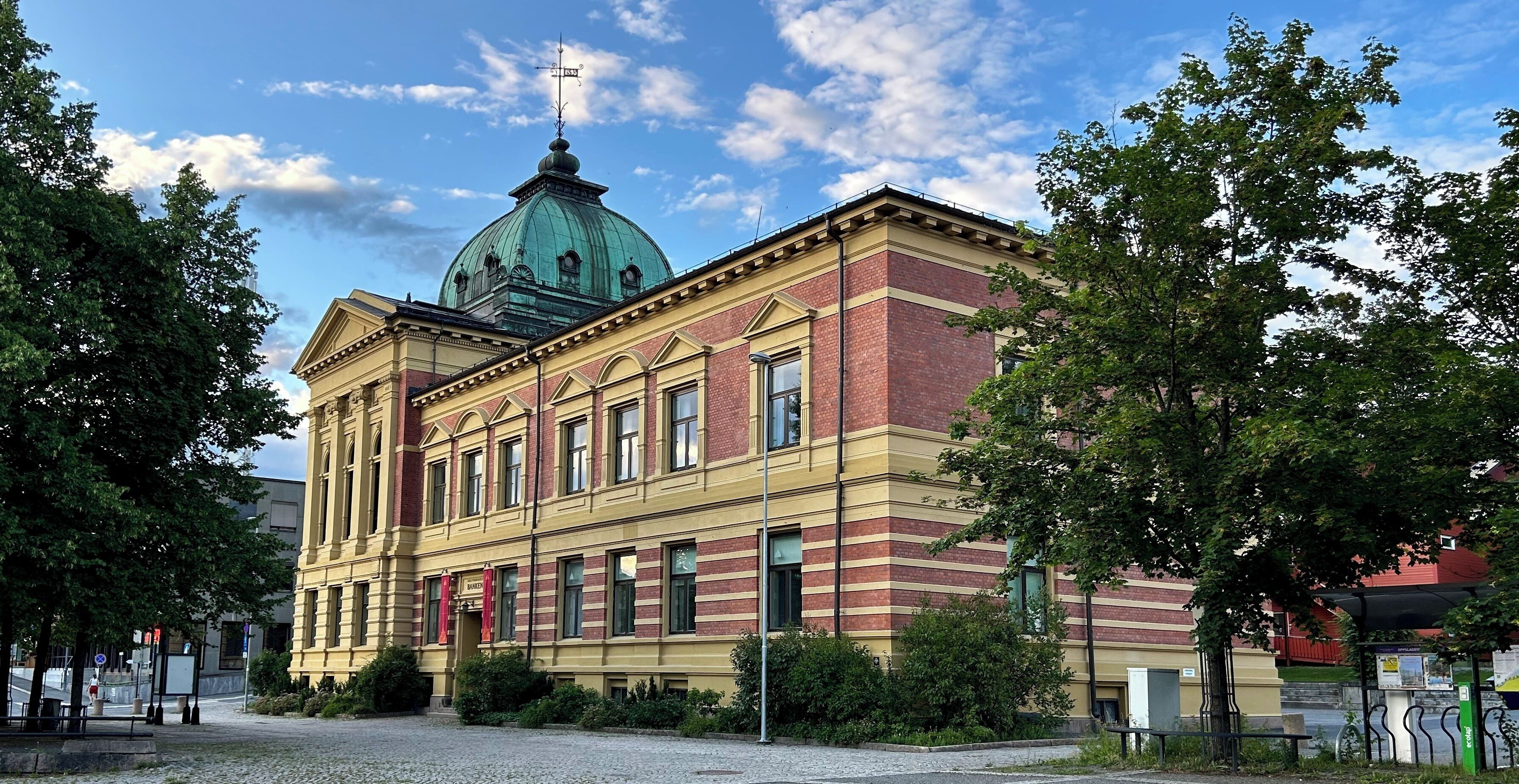 Ein historisches Gebäude mit einer grünen Kuppel, einer rot-gelben Fassade und einem gepflasterten Innenhof.
