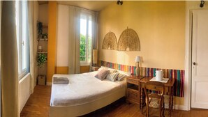 Un dormitorio con cama, mesita de noche, lámpara, silla y ventana con cortinas.