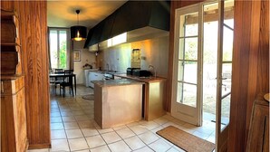 Una cocina con una isla central, un comedor con mesa y sillas, y vistas a través de un ventanal.