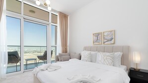 Ein Hotelzimmer mit einem großen Bett, einem Balkon mit Stühlen und zwei abstrakten Bildern an der Wand.
