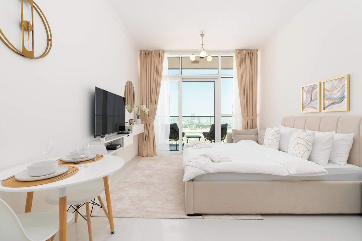 Ein modernes Hotelzimmer mit Bett, Fernseher, Esstisch mit Stühlen, Balkon mit Aussicht und einem großen Fenster.