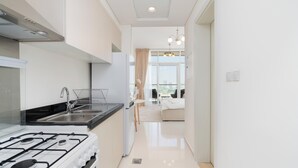 Eine moderne Küche mit Gaskochfeld, Spüle aus Edelstahl und Blick in einen Wohnbereich mit Sofa und Fenster zur Stadt.