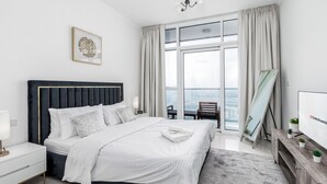Ein modernes Hotelzimmer mit einem großen Bett, einem Nachttisch, einem Tischchen, einem Fernseher, einem Fenster mit Vorhängen und Blick auf die Stadt.