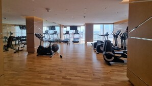 Ein geräumiger Fitnessraum mit verschiedenen Cardiogeräten, Krafttrainingsgeräten und einer großen Spiegelwand.
