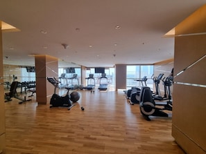 Ein geräumiger Fitnessraum mit verschiedenen Cardiogeräten, Krafttrainingsgeräten und einer großen Spiegelwand.