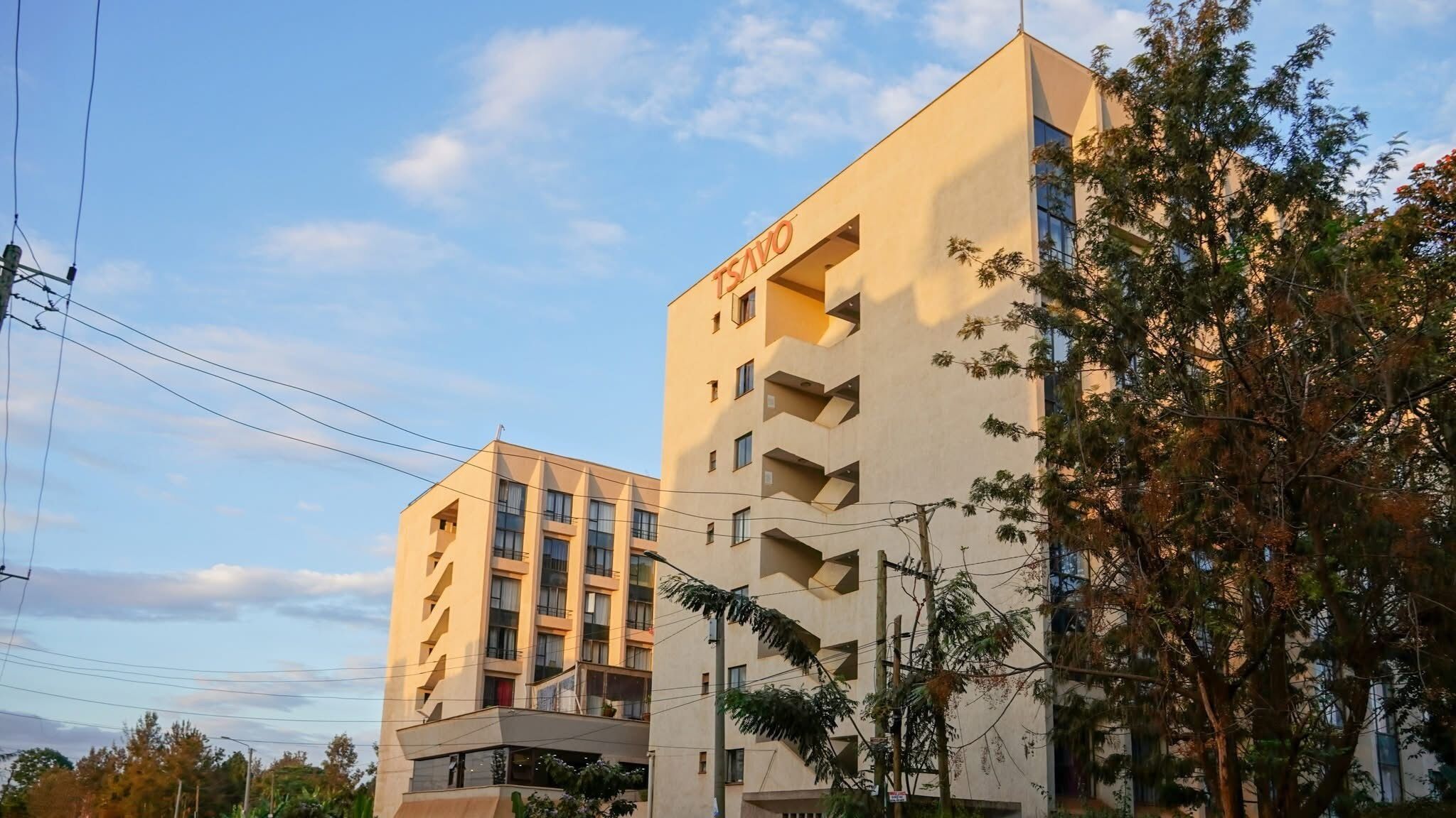 A multi-story building with the name 'TSAVO' on the facade, featuring balconies and a flat roof.