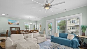 A living room with a ceiling fan, a blue sofa, a beige sofa, and a patterned rug. - Steps to Sand, Ocean Views, Water Park & Golf Cart (Myrtle Beach)