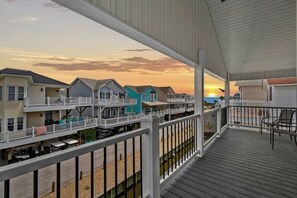 A balcony with a view of a row of houses and the sunset. - Steps to Sand, Ocean Views, Water Park and Grill (Myrtle Beach)