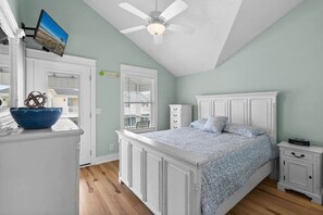 A bedroom with a large bed, a ceiling fan, a television on the wall, and a view of the outside. - Steps to Sand, Ocean Views, Water Park and Grill (Myrtle Beach)