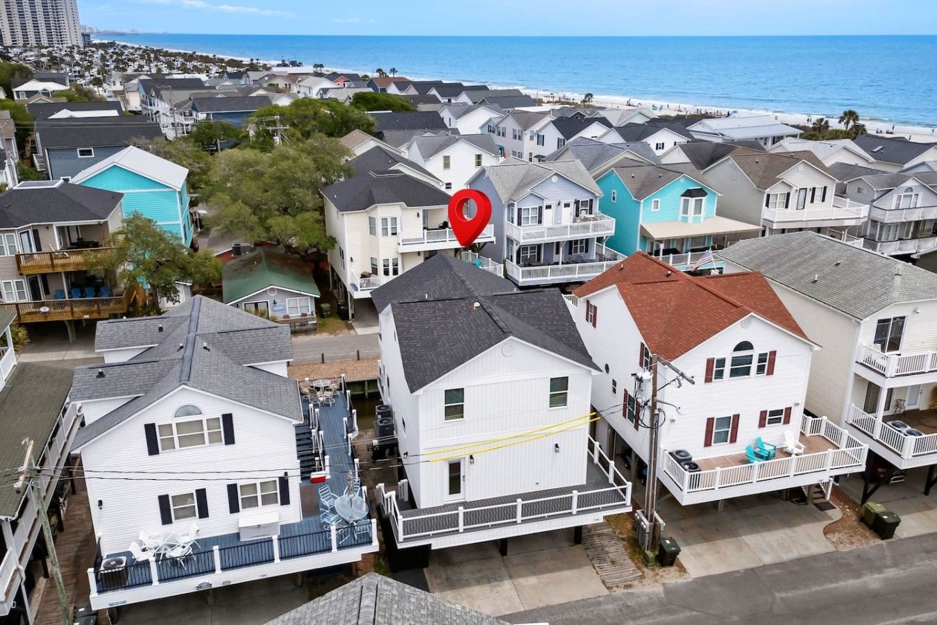 A coastal residential area with houses, some with balconies, and a beach in the background.