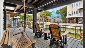 A covered outdoor area with wooden benches and chairs, a swing, and a view of residential buildings. - Steps to Sand, Ocean Views, Water Park & Golf Cart (Myrtle Beach)