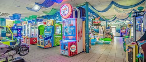 Un salón de juegos recreativos en el interior con diversas máquinas, incluidas máquinas de garra y juegos de carreras.