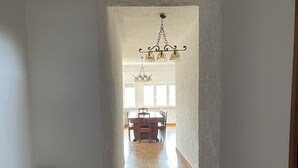 A hallway with a radiator, patterned floor, and a dining area with a chandelier.