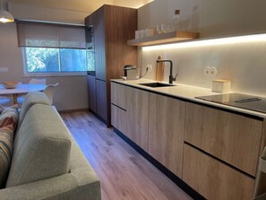 Eine moderne Küche mit Holzschränken, einer schwarzen Arbeitsplatte und einem Fenster mit Tageslicht.