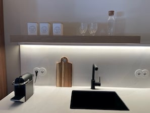 Eine moderne Küche mit integrierter Kaffeemaschine, einem Spülbecken und einer Holz-Schneidebrett.