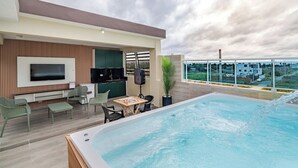 A rooftop pool with a flat-screen TV, outdoor seating, and a city view.