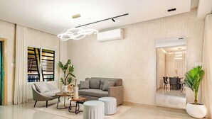 A modern living room with a grey sofa, a round coffee table, and a potted plant.