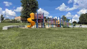 Ein Spielplatz mit einer gelben Spirale Rutsche, einer Kletterkonstruktion und einem umzäunten Bereich.