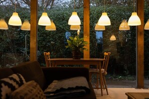 Ein gemütliches Zimmer mit Holztisch, Stühlen und hängenden Pendelleuchten.