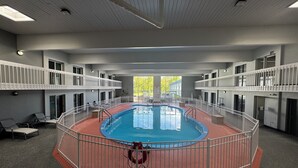 Una piscina interior con borde rojo, rodeada de barandillas blancas y varios balcones.