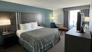 Una habitación de hotel con una cama grande, un escritorio con computadora, un televisor y una silla.