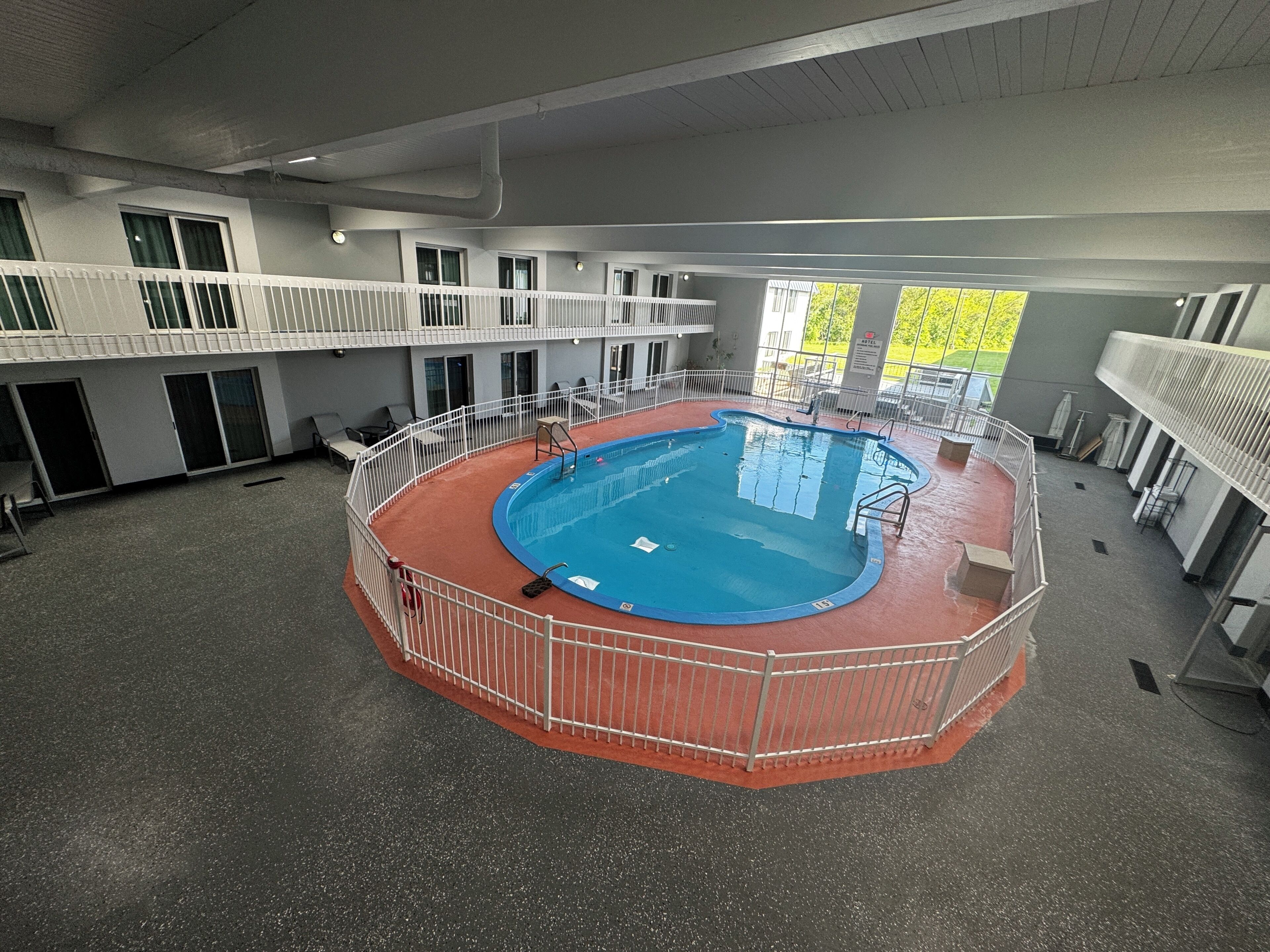 Una amplia piscina interior con borde rojo, rodeada por una barandilla blanca.