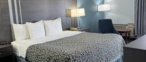 Habitación de hotel con una cama grande, dos mesitas de noche, un escritorio con silla, una lámpara y un reloj.