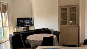 A dining area with a table, chairs, a television, a cabinet, and a window. - Lake house 40 minutes from Peschiera Del Garda, comfortably sleeps up to 4 people. (Mantova)