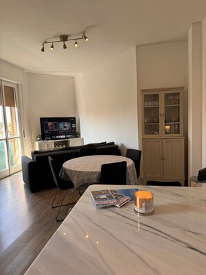 A dining area with a table, chairs, a television, a cabinet, and a window. - Lake house 40 minutes from Peschiera Del Garda, comfortably sleeps up to 4 people. (Mantova)