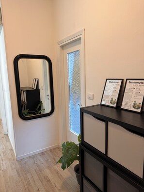 A hallway with a mirror, a door with frosted glass, and a black console with welcome signs. - Lake house 40 minutes from Peschiera Del Garda, comfortably sleeps up to 4 people. (Mantova)