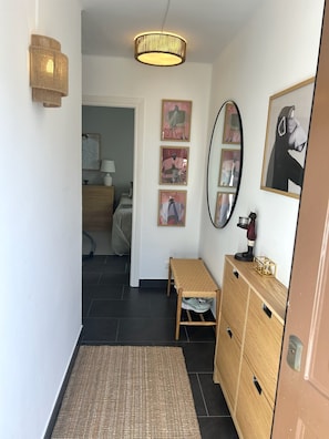 En hall med en träbänk, en spegel och konstverk på väggarna.