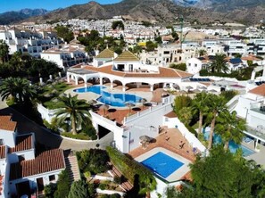 A resort with multiple swimming pools, palm trees, and a mountainous backdrop. - Capistrano Playa Luxe by the Sea - Nerja (Nerja)