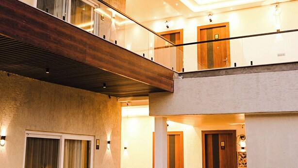 A multi-level building with a balcony, outdoor seating area, and a door leading to an interior space. - Ramana on the Ganges (Tapovan, Rishikesh)