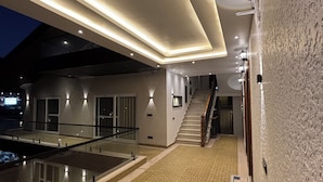 A modern indoor pool area with a glass barrier, a staircase, and wicker chairs. - Ramana on the Ganges (Tapovan, Rishikesh)