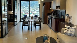 Un soggiorno moderno con zona pranzo, cucina e ampie finestre che offrono vista sulla città.