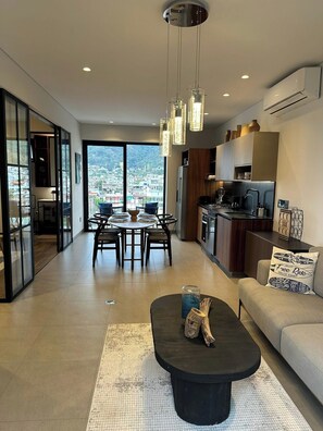Ein modernes Wohnzimmer mit Essbereich, Küche und großen Fenstern mit Blick auf die Stadt.