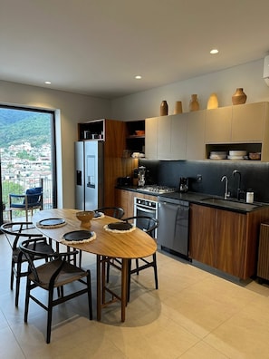 Eine moderne Küche mit Essbereich, großen Fenstern und Blick auf eine Stadtlandschaft.