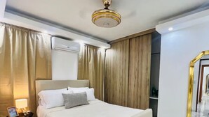 A hotel room with a bed, a nightstand, a lamp, a ceiling fan, and a mirror with a gold frame. - Private swimming pool in punta cana, electricity included (Punta Cana)