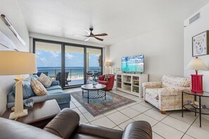 Ein Wohnzimmer mit Sofa, Sessel, Couchtisch, Fernseher und Meerblick.