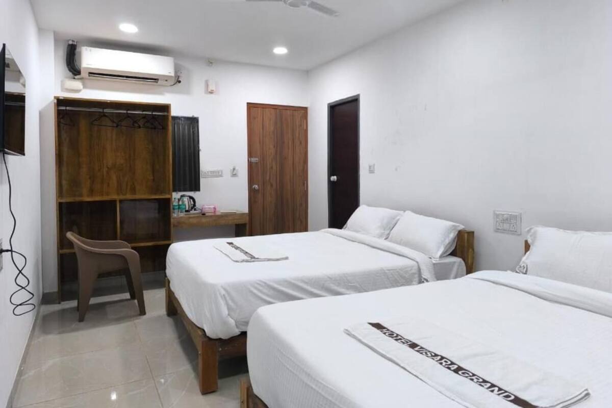 Habitación de hotel con dos camas, un escritorio, un armario y un ventilador de techo.