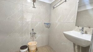 Un baño con lavamanos, espejo, toallero, ducha e inodoro.